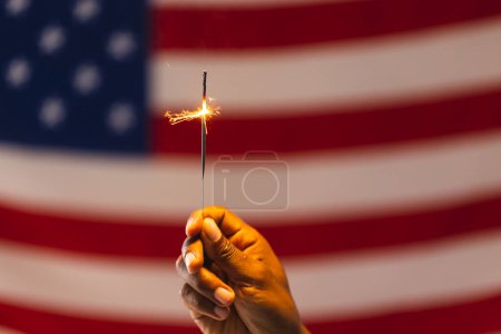 Téléchargez les photos : Main de l'homme biracial tenant scintillant et drapeau des États-Unis d'Amérique avec espace de copie. Patriotisme américain, fête de l'indépendance et concept de tradition. - en image libre de droit