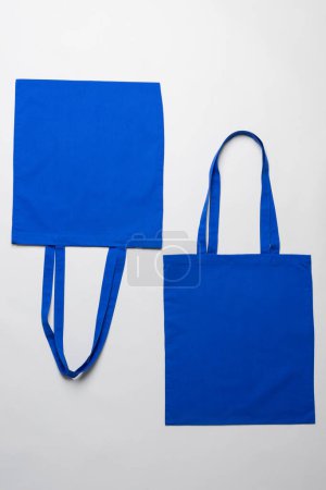 Téléchargez les photos : Vue en angle élevé de deux sacs en toile bleue avec espace de copie sur fond blanc. Sacs et concept de mode. - en image libre de droit