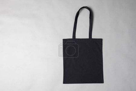 Foto de Vista en ángulo alto de la bolsa de lona negra con espacio para copiar sobre fondo gris. Bolsas y concepto de moda. - Imagen libre de derechos