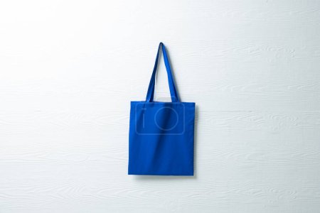 Foto de Primer plano de la bolsa de lona azul colgante con espacio de copia sobre fondo azul. Bolsas de compras ecológicas y concepto de moda. - Imagen libre de derechos