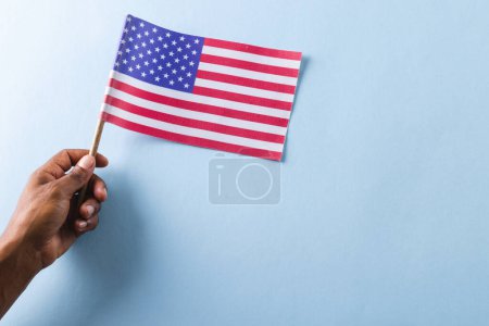 Foto de Mano de hombre biracial sosteniendo bandera de estados unidos de América con espacio de copia. Patriotismo americano, día de la independencia y concepto de tradición. - Imagen libre de derechos