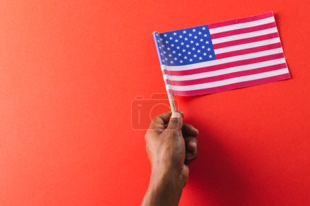Téléchargez les photos : Main de l'homme biracial tenant le drapeau des États-Unis d'Amérique avec espace de copie. Patriotisme américain, fête de l'indépendance et concept de tradition. - en image libre de droit