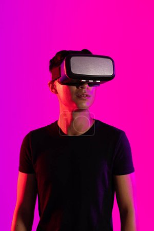 Photo for Asian man using vr headset in studio with purple light and copy space. Virtual reality and digital interface technology. - Royalty Free Image