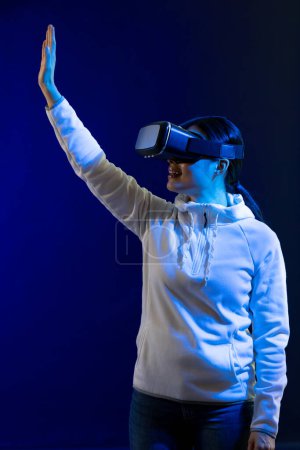 Photo for Happy asian woman using vr headset in studio with blue light. Virtual reality and digital interface technology. - Royalty Free Image