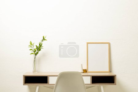 Foto de Marco de madera vacío con espacio de copia y planta en maceta en el escritorio contra la pared blanca. Simular plantilla de marco, diseño de interiores y decoración. - Imagen libre de derechos