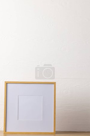 Téléchargez les photos : Vertical de cadre en bois vide avec espace de copie sur la table contre le mur blanc. Modèle de cadre maquillé, design d'intérieur et décoration. - en image libre de droit