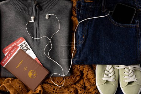 Photo for Close up of gray jumper, jeans, beige shoes, passport, tickets, smartphone and earphones. Travel and vacation. - Royalty Free Image