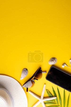 Photo for Straw hat, sunglasses, smartphone, plant and seashells on yellow background with copy space. Travel and vacation. - Royalty Free Image