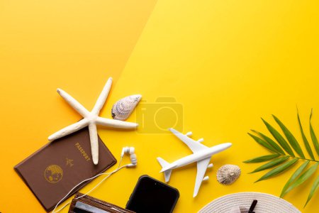 Téléchargez les photos : Modèle d'avion, coquillages, passeport, chapeau de paille et smartphone sur fond jaune avec espace de copie. Voyages, transports et vacances. - en image libre de droit
