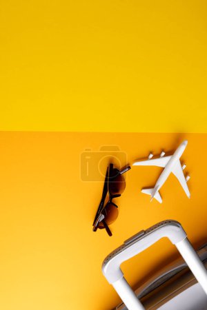 Foto de Modelo de avión, gafas de sol y maleta sobre fondo amarillo con espacio para copiar. Viajes, transporte y vacaciones. - Imagen libre de derechos