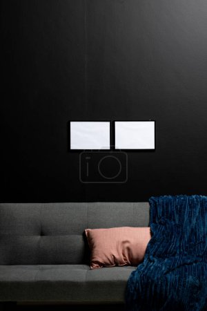 Photo for Vertical of empty white canvases with copy space on black wall in room with couch. Mock up frame template, interior design and decoration. - Royalty Free Image