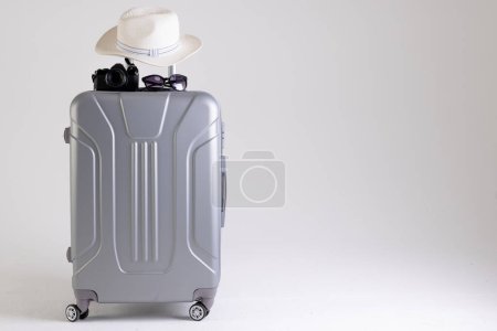 Téléchargez les photos : Valise avec chapeau de paille, lunettes de soleil et appareil photo sur fond blanc avec espace de copie. Voyages et vacances. - en image libre de droit
