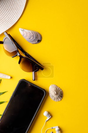 Photo for Straw hat, sunglasses, smartphone, plant and seashells on yellow background with copy space. Travel and vacation. - Royalty Free Image