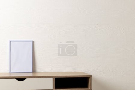 Téléchargez les photos : Cadre blanc vide avec espace de copie sur la table contre le mur blanc. Modèle de cadre maquillé, design d'intérieur et décoration. - en image libre de droit