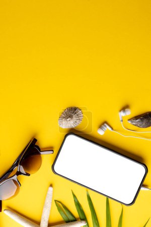Foto de Smartphone con espacio de copia en la pantalla, gafas de sol, planta, conchas marinas sobre fondo amarillo. Viajes y vacaciones. - Imagen libre de derechos