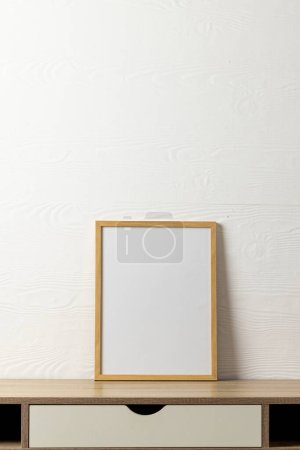Téléchargez les photos : Vertical de cadre en bois vide avec espace de copie sur le bureau contre le mur blanc. Modèle de cadre maquillé, design d'intérieur et décoration. - en image libre de droit