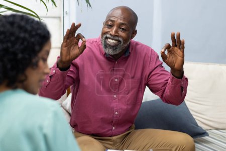 Téléchargez les photos : Heureux patient afro-américain masculin qui suit une thérapie avec une thérapeute féminine biraciale. Santé mentale, thérapie et counselling. - en image libre de droit