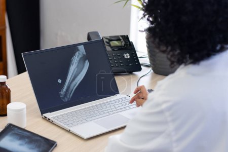 Téléchargez les photos : Médecin de naissance utilisant un ordinateur portable avec une radiographie à l'écran au bureau du médecin. Hôpital, médecine, santé et communication. - en image libre de droit