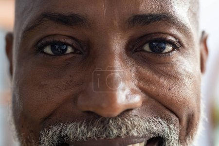 Foto de Retrato de un feliz médico afroamericano mirando a la cámara y sonriendo en el consultorio del doctor. Hospital, medicina y asistencia sanitaria. - Imagen libre de derechos