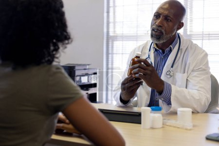 Téléchargez les photos : Médecin afro-américain et patiente biraciale parlant au cabinet du médecin. Hôpital, médecine et santé. - en image libre de droit