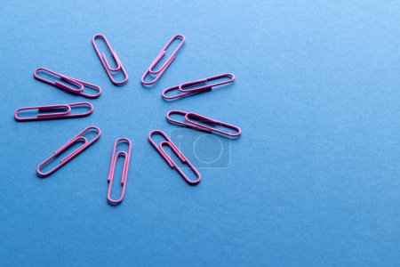 Photo for Close up of pink paper clips in circle and copy space on blue background. School materials, organising, learning, school and education concept. - Royalty Free Image