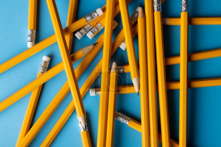 Téléchargez les photos : Gros plan de la pile de crayons jaunes avec gommes sur fond bleu. Écrire, dessiner, apprendre, concept scolaire et éducatif. - en image libre de droit