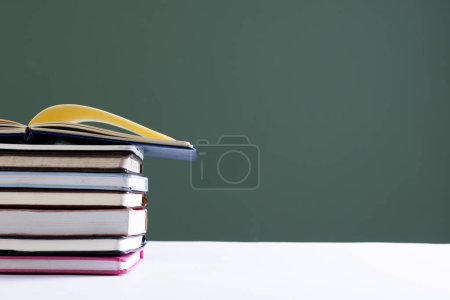 Photo for Close up of stack of books and notebooks with copy space on green background. Reading, learning, school and education concept. - Royalty Free Image