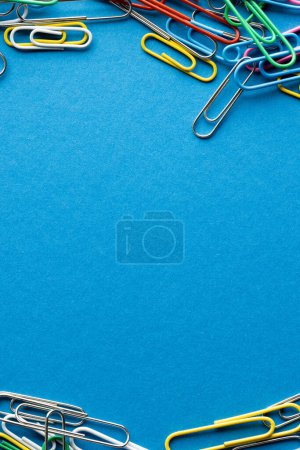 Photo for Close up of stack of multi coloured paper clips and copy space on blue background. School materials, organising, learning, school and education concept. - Royalty Free Image