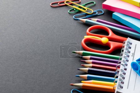 Close up of coloured pencils and school materials with copy space on black background. School materials, writing, colouring, drawing, learning, school and education concept.