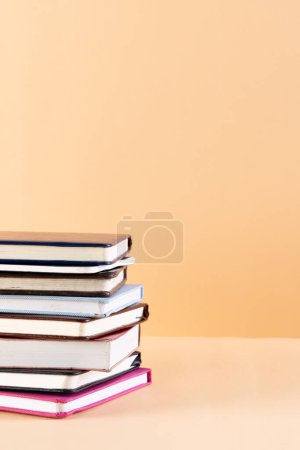 Téléchargez les photos : Gros plan de la pile de livres et carnets avec espace de copie sur fond orange. Concept de lecture, d'apprentissage, d'école et d'éducation. - en image libre de droit