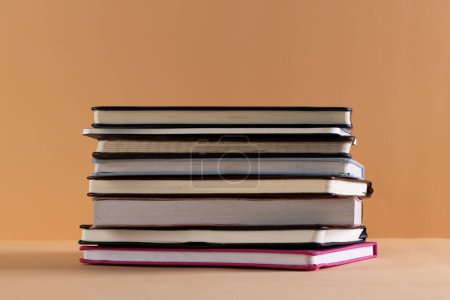Photo for Close up of stack of books and notebooks with copy space on orange background. Reading, learning, school and education concept. - Royalty Free Image