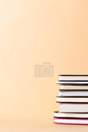 Photo for Close up of stack of books and notebooks with copy space on orange background. Reading, learning, school and education concept. - Royalty Free Image
