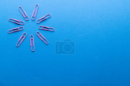 Photo for Close up of pink paper clips in circle and copy space on blue background. School materials, organising, learning, school and education concept. - Royalty Free Image