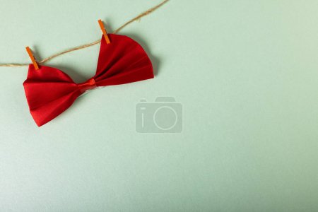 Téléchargez les photos : Vue grand angle du nœud papillon rouge suspendu avec des pinces à linge sur corde à linge sur fond blanc. Espace de copie, homme, mode, concept d'élégance. - en image libre de droit
