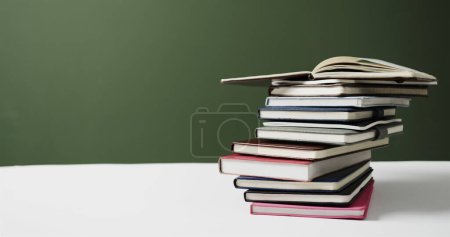 Close up of stack of books with copy space on green background. Reading, learning, school and education concept.