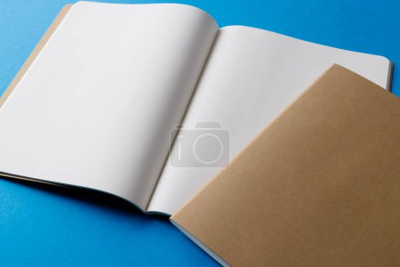 Photo for Close up of beige notebook and open book with copy space on blue background. Literature, reading, writing, leisure time and books. - Royalty Free Image