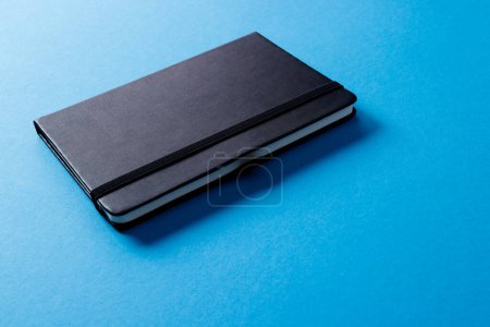 Téléchargez les photos : Gros plan du carnet noir avec espace de copie sur fond bleu. Littérature, lecture, écriture, loisirs et livres. - en image libre de droit