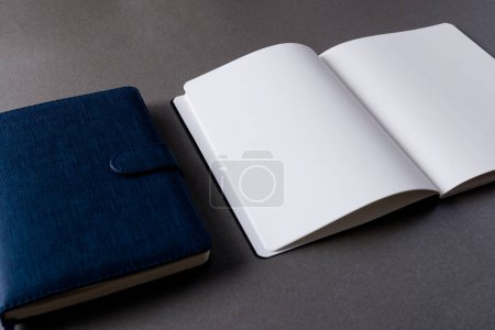 Foto de Primer plano de cuaderno azul y libro abierto con espacio de copia sobre fondo gris. Literatura, lectura, escritura, tiempo libre y libros. - Imagen libre de derechos