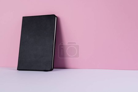 Photo for Close up of black notebook with copy space on pink background. Literature, reading, writing, leisure time and books. - Royalty Free Image