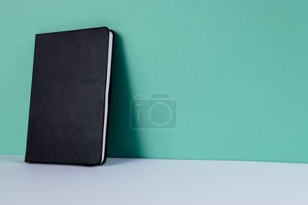 Photo for Close up of black notebook with copy space on green background. Literature, reading, writing, leisure time and books. - Royalty Free Image