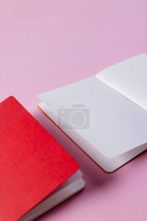Foto de Primer plano de cuaderno rojo y libro abierto con espacio de copia sobre fondo rosa. Literatura, lectura, escritura, tiempo libre y libros. - Imagen libre de derechos