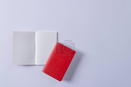 Foto de Primer plano del cuaderno rojo y libro abierto con espacio de copia sobre fondo blanco. Literatura, lectura, escritura, tiempo libre y libros. - Imagen libre de derechos
