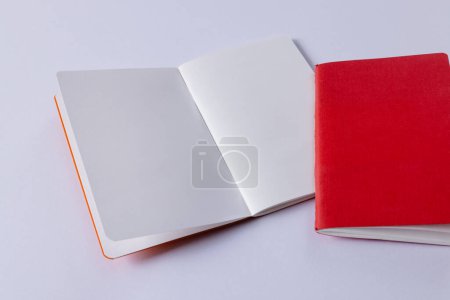 Foto de Primer plano del cuaderno rojo y libro abierto con espacio de copia sobre fondo blanco. Literatura, lectura, escritura, tiempo libre y libros. - Imagen libre de derechos