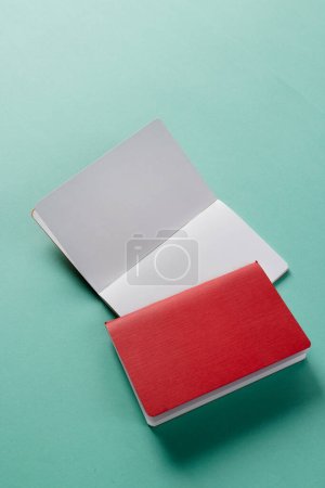 Photo for Close up of red notebook and open book with copy space on green background. Literature, reading, writing, leisure time and books. - Royalty Free Image