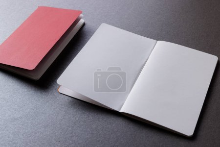 Foto de Primer plano de cuaderno rojo y libro abierto con espacio de copia sobre fondo gris. Literatura, lectura, escritura, tiempo libre y libros. - Imagen libre de derechos
