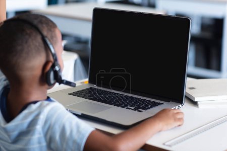 Foto de African american schoolboy with headphones having laptop video call with copy space. School, education, technology and online learning. - Imagen libre de derechos