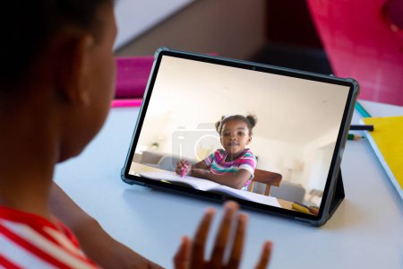 Photo for African american schoolgirls waving hand and having tablet video call. School, education, technology and online learning. - Royalty Free Image