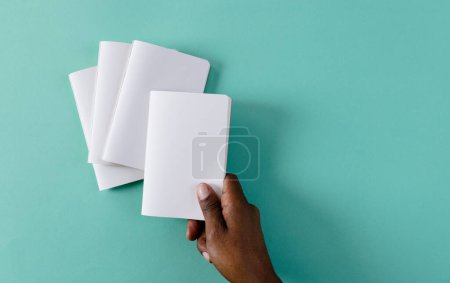 Téléchargez les photos : Main d'homme biracial tenant un carnet sur des carnets avec espace de copie sur fond vert. Littérature, lecture, loisirs et livres. - en image libre de droit