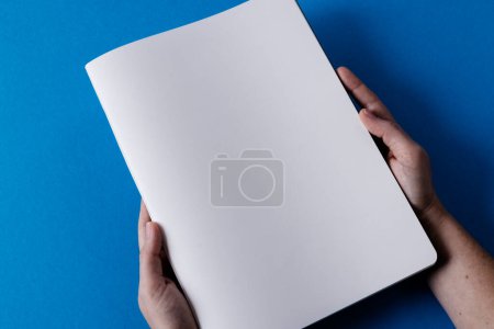Photo for Hands of caucasian woman holding book with copy space on blue background. Literature, reading, leisure time and books. - Royalty Free Image