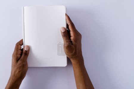 Téléchargez les photos : Mains de l'homme biracial tenant le livre avec l'espace de copie sur fond gris. Littérature, lecture, loisirs et livres. - en image libre de droit